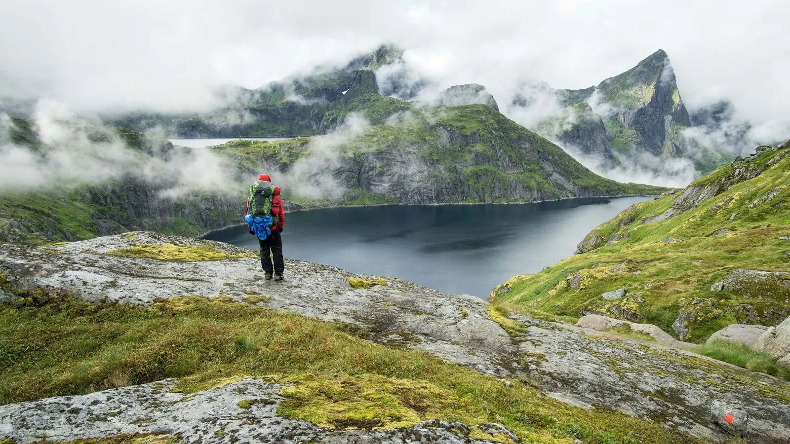 A hiker looking out over a misty mountain lake