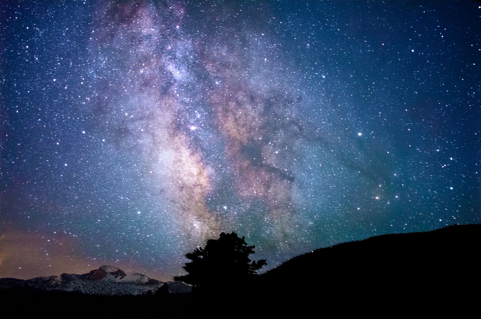 Starry night sky over a mountain silhouette